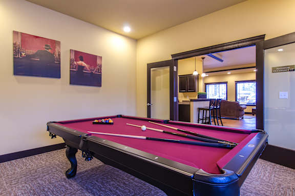 A pool table in a room with two pictures on the wall.