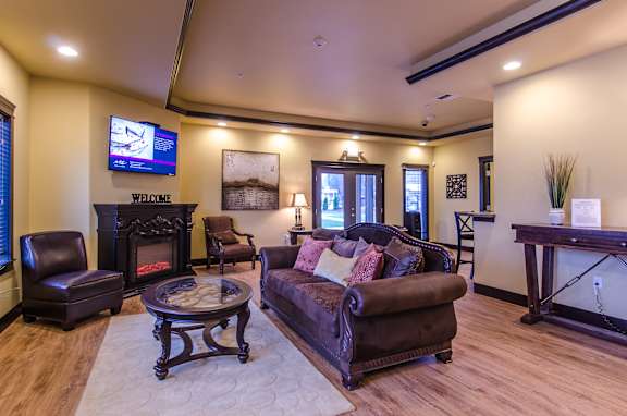 Floor Plan  A living room with a brown leather couch and a fireplace.