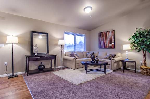 A living room with a couch, chair, and a table with a vase on it.