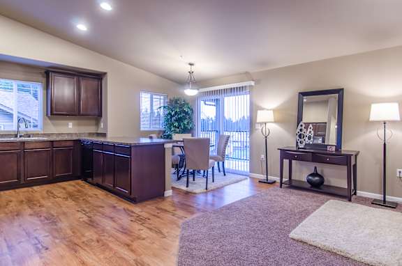 A well-lit kitchen with wooden floors and a dining area with a table and chairs.