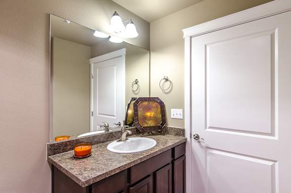 A bathroom with a sink, mirror, and candle.