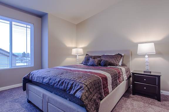 A bedroom with a bed, nightstand, and window.