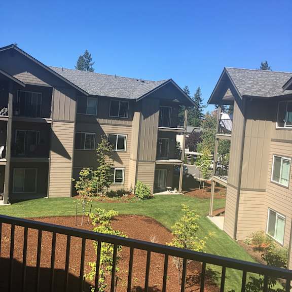 Apartment complex with brown siding and green trees in the background.