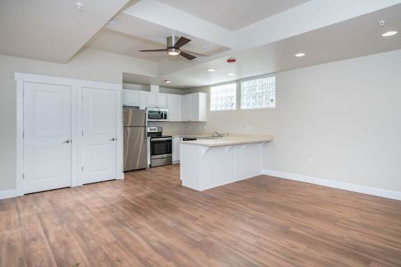 A kitchen with white cabinets and a wooden floor.