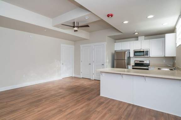 A kitchen with white cabinets and a wooden floor.
