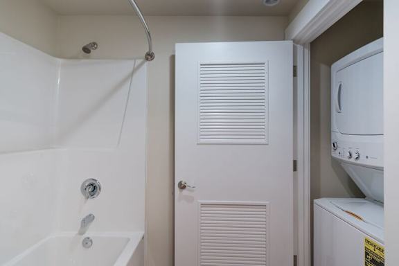 A white bathroom with a tub, shower, and a white door.