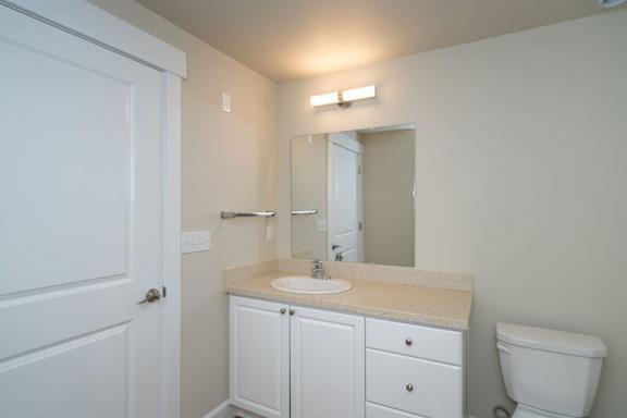 A bathroom with a white toilet, sink, and cabinets.