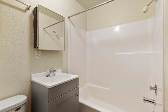 A white sink is on a cabinet next to a toilet in a bathroom.