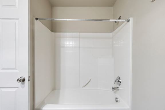 A white bathroom with a tub and a door.