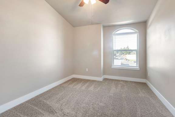 A room with a carpeted floor and a window with blinds.