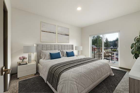 A bedroom with a large bed and a balcony overlooking trees.