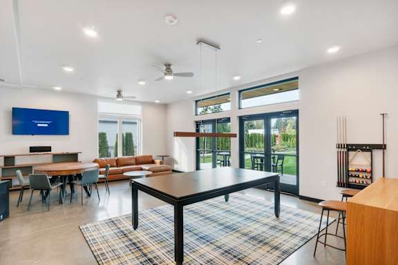 A modern living room with a black table and a flat screen TV mounted on the wall at The Hub Apartments, Lacey, 98503