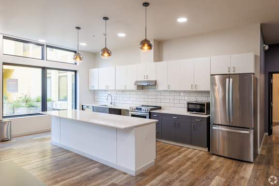A modern kitchen with a white island and stainless steel appliances.