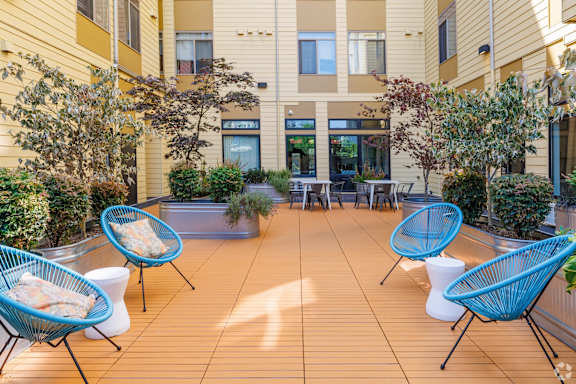 A patio with blue chairs and white cushions.