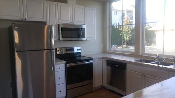 A kitchen with a stainless steel refrigerator, microwave, oven, and dishwasher.