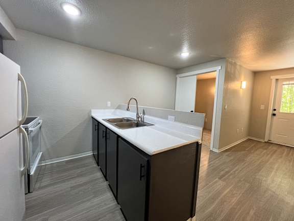 A kitchen with a white sink and brown cabinets.