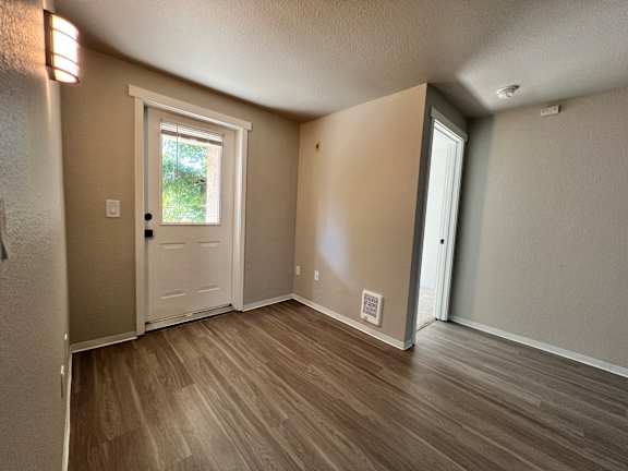 A room with a white door and wooden flooring.
