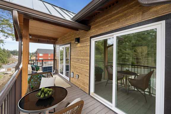 A balcony with a table and chairs overlooking a red building.