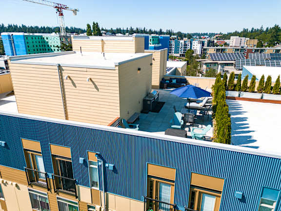 A blue building with a balcony and a tree in front of it.