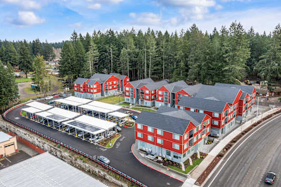 A large red building complex with a parking lot in front.
