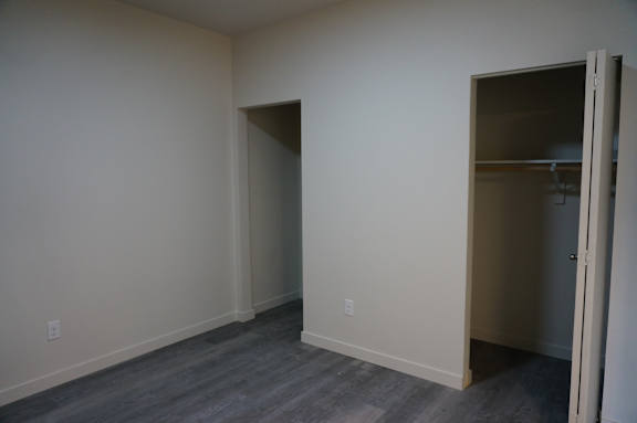 A room with a grey floor and white walls with two open doors.