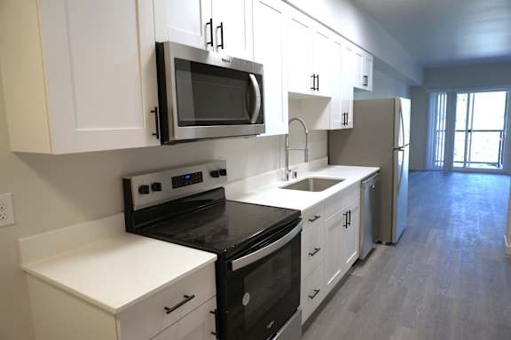 A kitchen with white cabinets and black appliances.