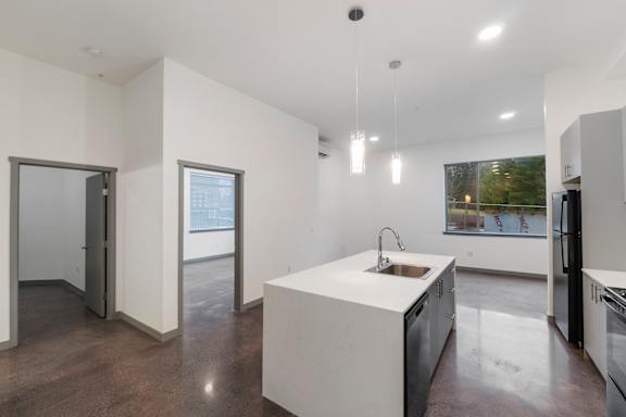 a kitchen and living room with white walls and concrete floors