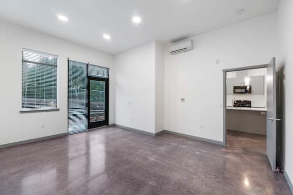 a spacious living room with white walls and a concrete floor