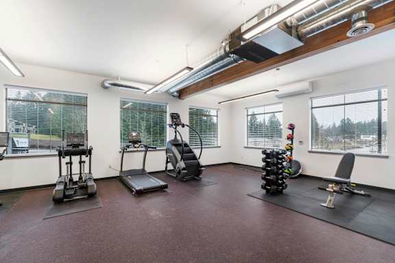 A gym with a variety of equipment including treadmills, stationary bikes, and weight racks.