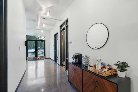 A black and white hallway with a round mirror on the wall.