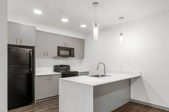A modern kitchen with a black refrigerator and white countertops.