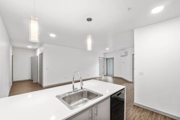 A modern kitchen with a white countertop and stainless steel sink.