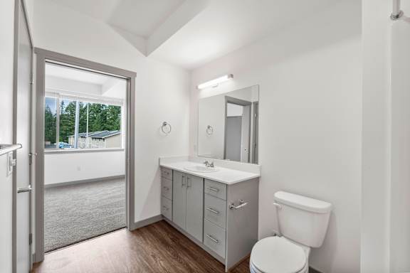 A white bathroom with a toilet, sink, and mirror.