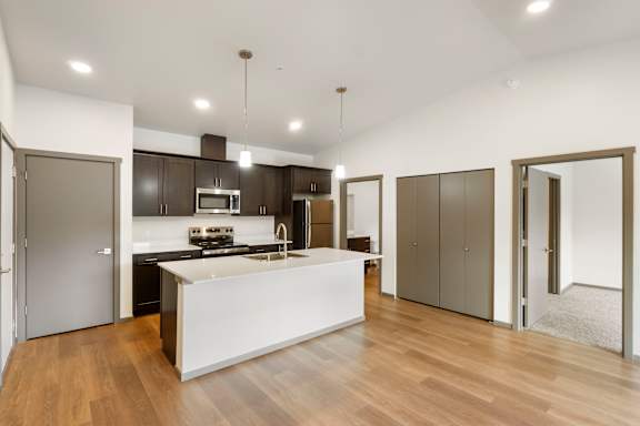 A modern kitchen with a white island and wooden floors.