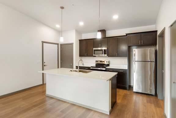 A modern kitchen with a white island and stainless steel appliances.