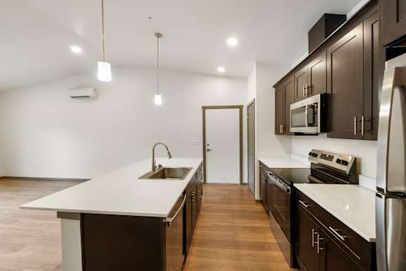 A modern kitchen with dark brown cabinets and white countertops.