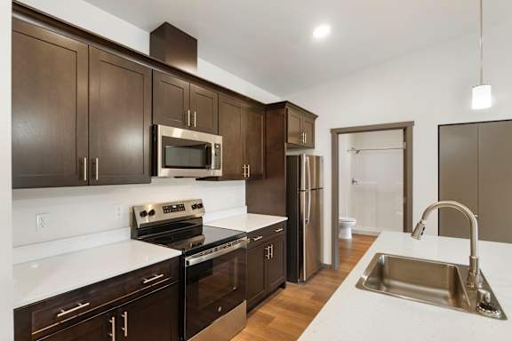A kitchen with dark brown cabinets and stainless steel appliances.