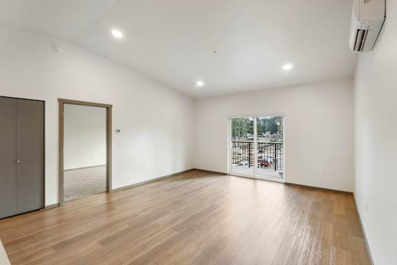 A room with wooden flooring and a window overlooking a parking lot.