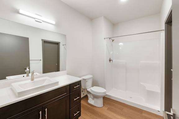 A white bathroom with a sink, toilet, and shower.