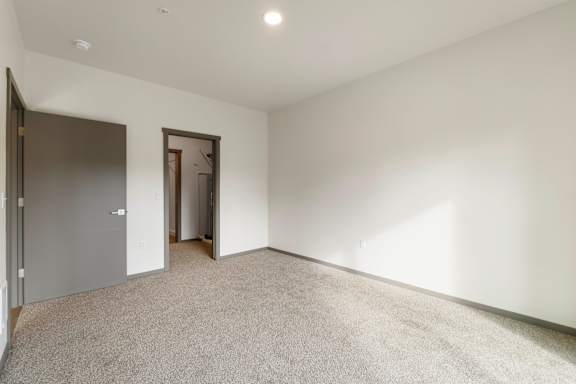A room with a carpeted floor and two doors.