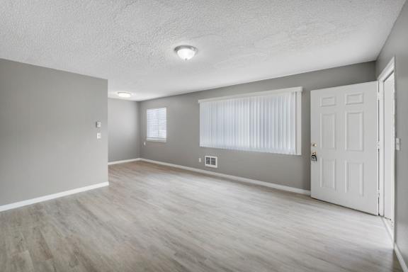 A room with a white door, grey walls, and a window with blinds.