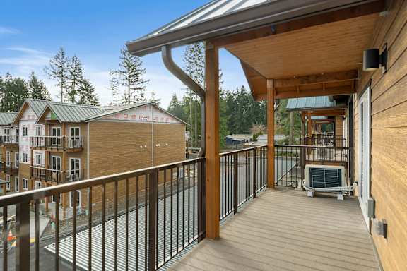 A wooden deck with a metal railing and a hot tub.