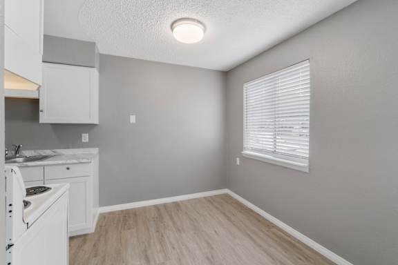 A kitchen area with a sink, cabinets, and a window with blinds.