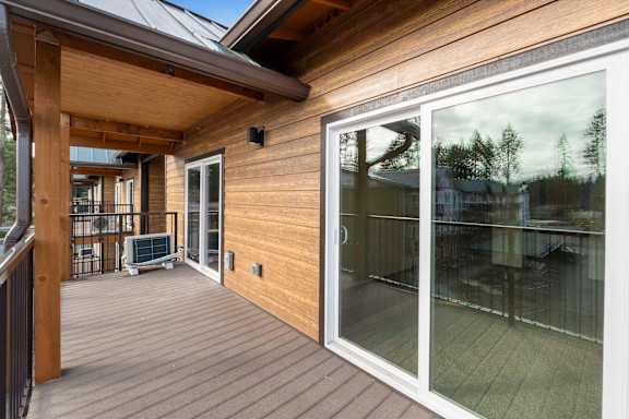 A wooden deck with a glass door leading to a patio.