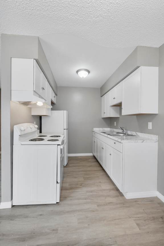 A white kitchen with a stove, oven, and sink.