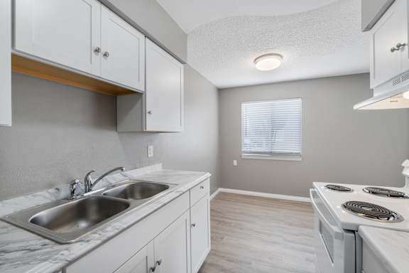 A kitchen with white cabinets and a marble countertop.