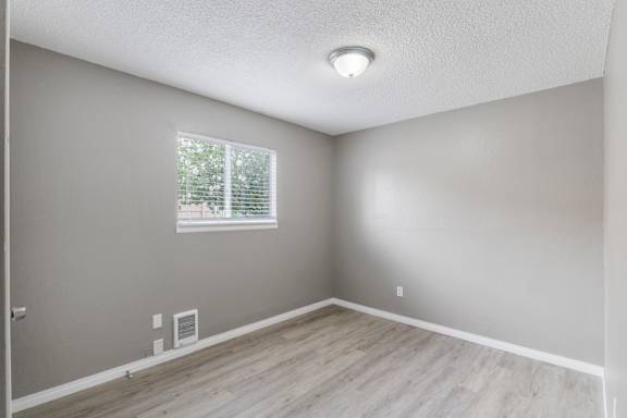A room with a window and a wooden floor.