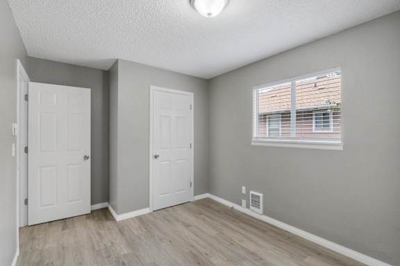 A room with two doors and a window with blinds.