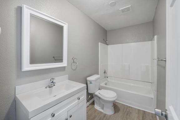 A white bathroom with a toilet, sink, and bathtub.