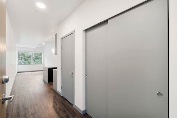 A hallway with a white door and a black bench.